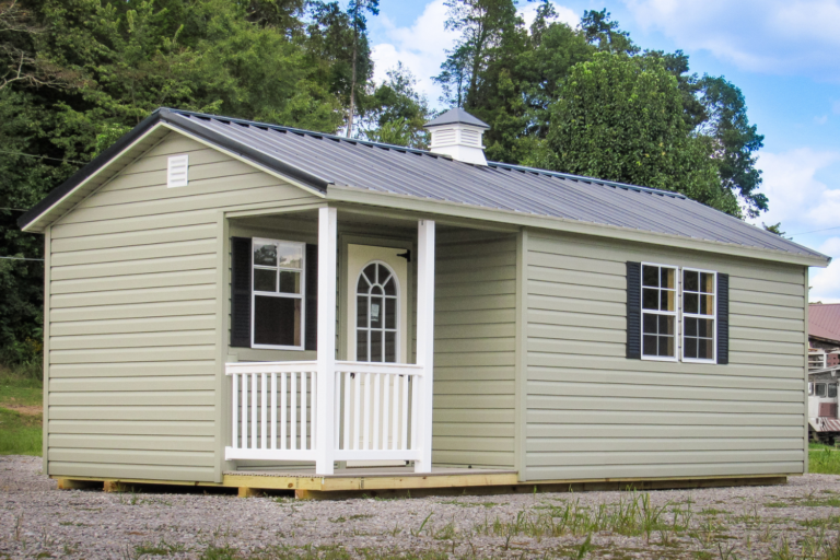 8x12 cabin side view green with black metal roof with cupola, two windows, and a white door