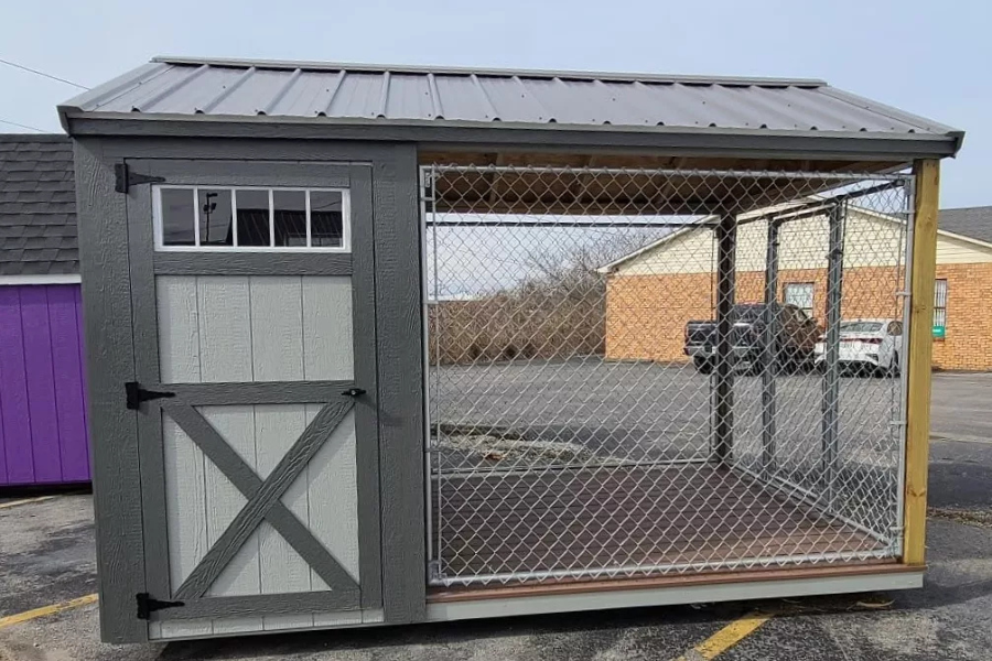 light gray and dark gray trimmed dog kennel with side door with transom windows attached run and gray metal roof sitting in parking lot how big should a dog kennel be example