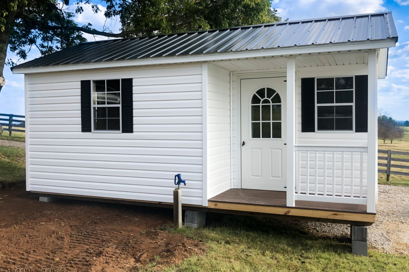 white 8x10 cabin with black roof and two windows and a white door
